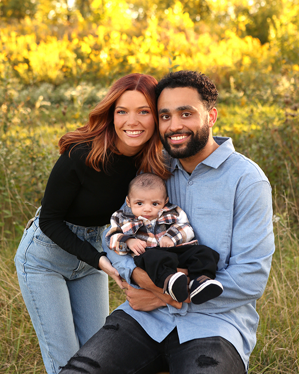 mom and dad snuggle baby boy and smile at camera for fall photoshoot in carmel