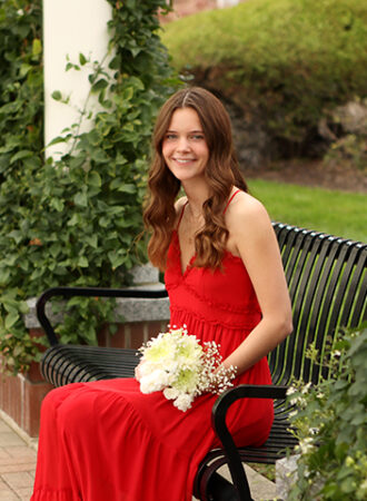 girl in red dress poses for senior pictures holding flowers
