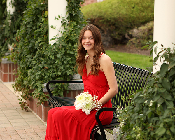 girl in red dress poses for senior pictures holding flowers