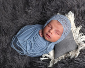 newborn wrapped in blue fabric wearing blue bonnet