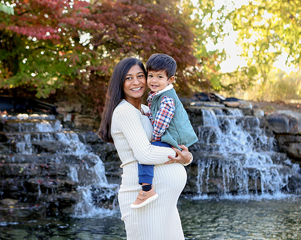 pregnant moms snuggles toddler in front of a waterfall in carmel indiana 