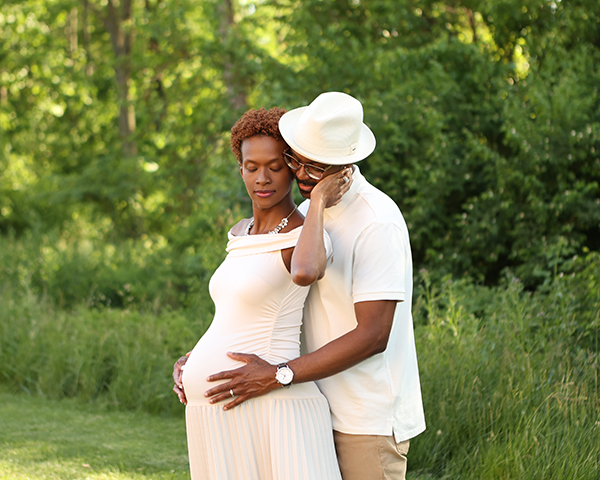 mom snuggles dad as he cradles her pregnant belly