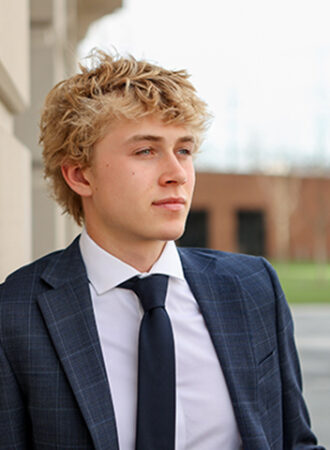 senior boy poses against concrete wall for portrait in westfield