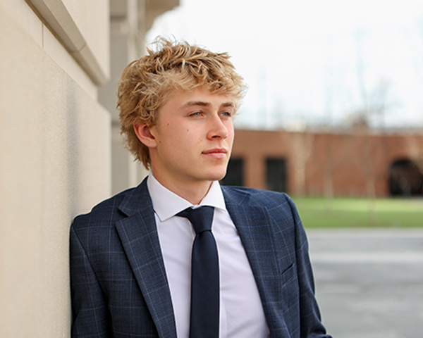 senior boy poses against concrete wall for portrait in westfield