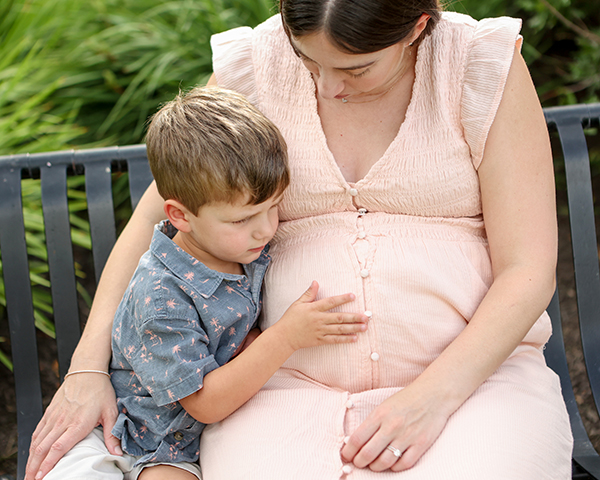 boy pats mom's pregnant belly